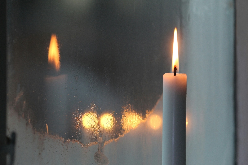 Advent candle, with its reflection in a window in the background