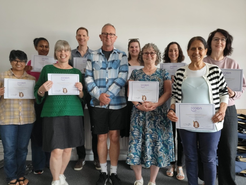 Avenue Child Contact Centre volunteers (8 women, 2 men) stand in a line, each holding up an award certificate