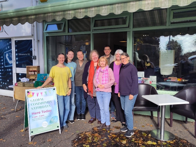 8 people stand outside Leigh Road Baptist Church's Living Room next to sign stating "Global Community Saturday - here today)
