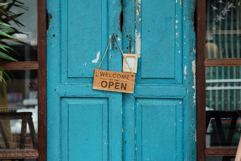 A blue door featuring a welcoming open sign, inviting visitors to enter