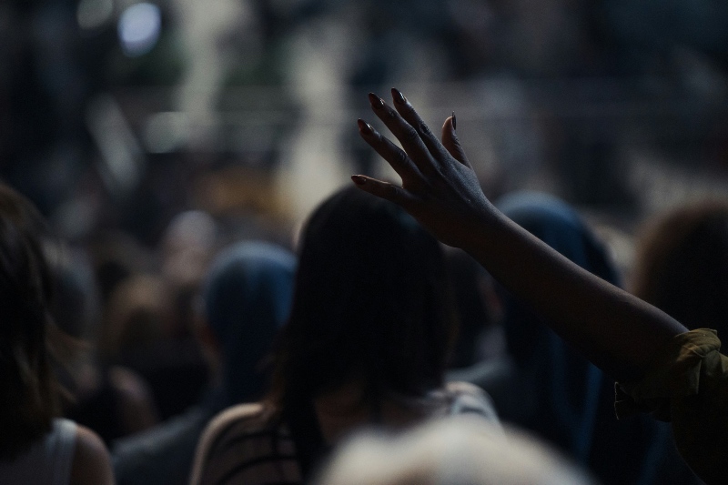 Worship event showing the backs of several heads and hands in the air 