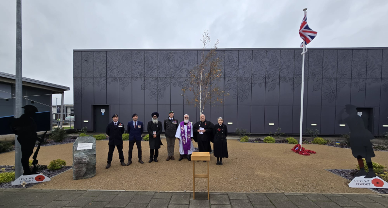 Airport chaplains stand in the specially created outdoor events space at East Midlands Airport, flanked by life size images of unknown soldiers with the words "Lest we forget" 