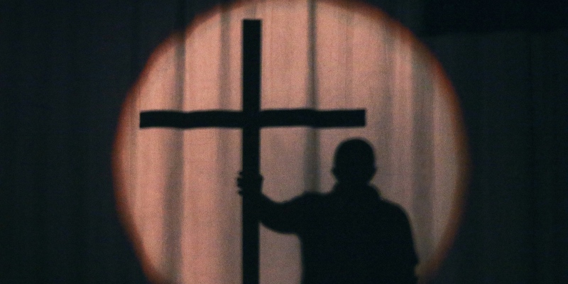 Silhouette of a man holding a Christian cross 