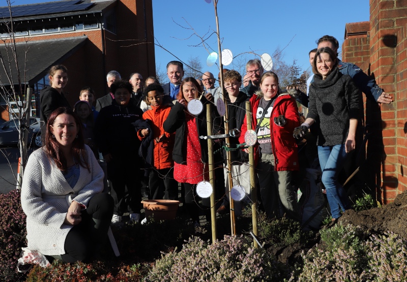 Members of the congregation and clergy gather round the newly planted silver birch tree to mark the church's 25th anniversary 